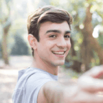 Young man smiling outdoors, illustrating that Peyronie’s disease can affect men of all ages, including younger adults.