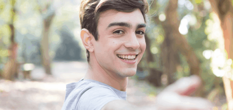 Young man smiling outdoors, illustrating that Peyronie’s disease can affect men of all ages, including younger adults.