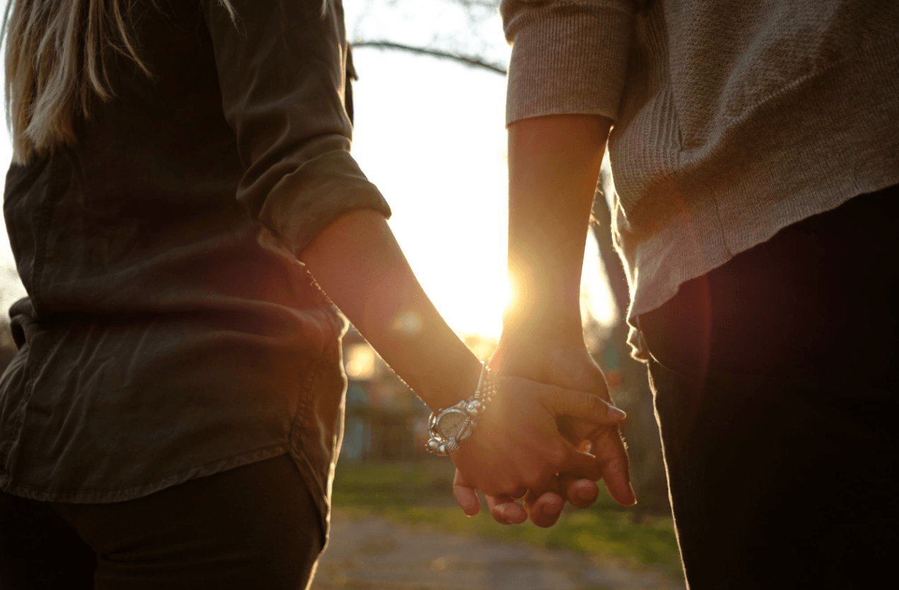 Couple holding hands outdoors at sunset, representing the impact Peyronie’s disease can have on confidence and intimate relationships.