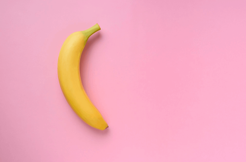 Single banana on a pink background, symbolising penile curvature becoming more noticeable over time.
