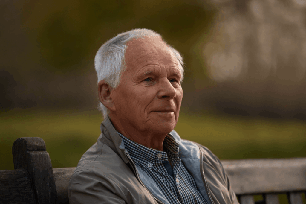 Older man sitting on a park bench, illustrating that Peyronie’s disease is often associated with older men but can affect younger adults too.